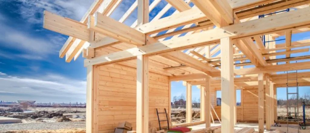 A new home build site with a variety of tools and wood stacked around the construction area. The sky is blue.
