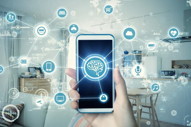 Hand holding a cell phone in front of a home scene surrounded by icons of various technologies