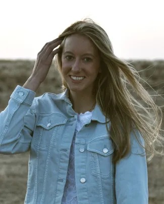 Young woman standing brushing her hair aside.