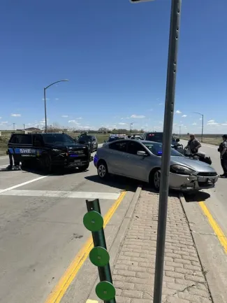 Car resting on a roadway median with a law enforcement vehicle being.