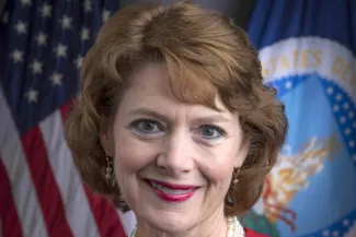Head shot of Sallie Clark in front of the United States and USDA flags