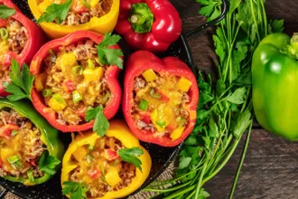 Tray of red and yellow peppers stuffed with rice and beans.