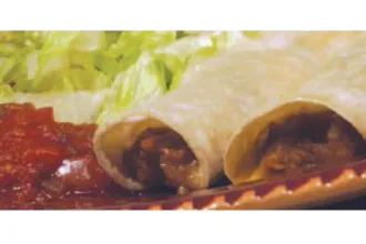 Extreme closeup of the ends of two bean enchiladas on a plate next to salsa and lettuce.
