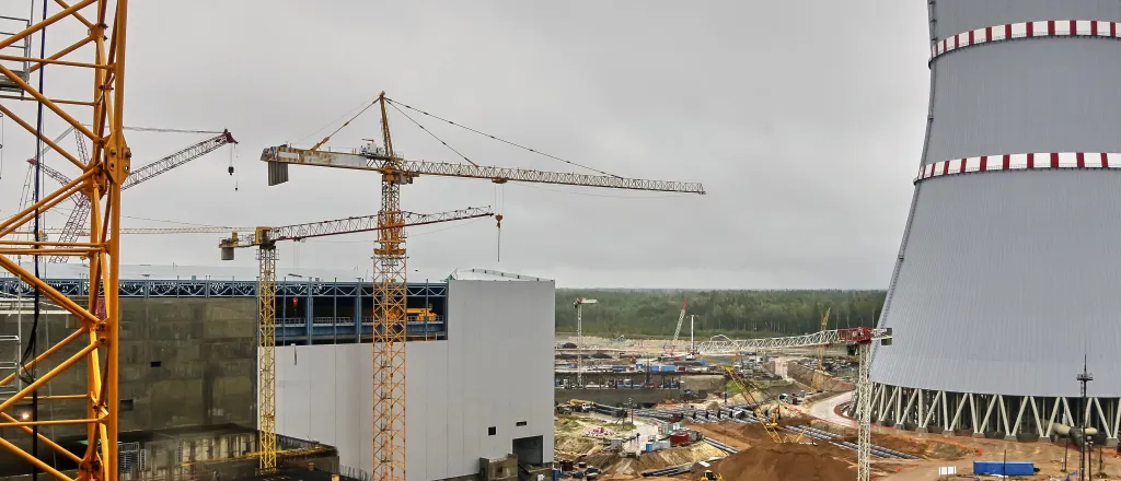 Construction cranes around a nuclear power plant and cooling tower