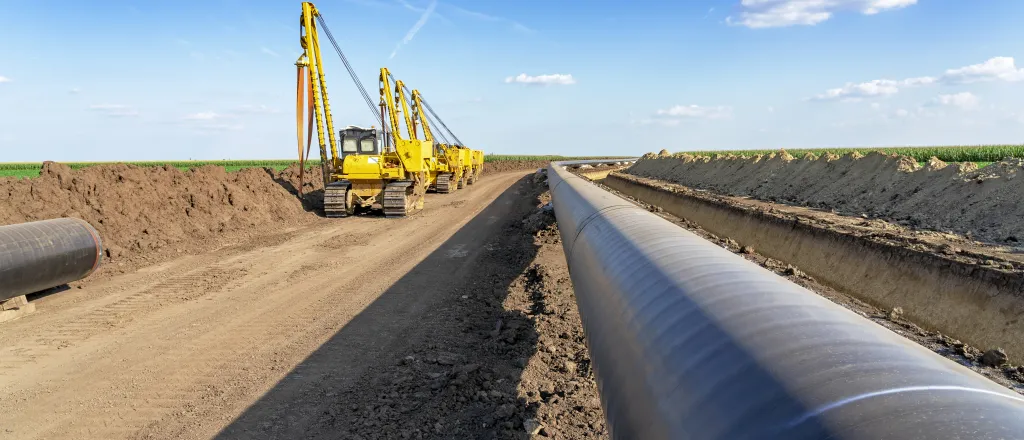 Pipeline being buried with heavy equipment in the background.