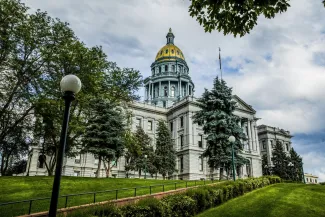Colorado State Capitol building with green trees and golden dome.