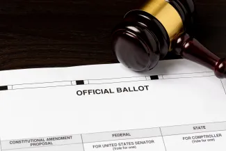 Court judge's gavel resting on an election ballot.