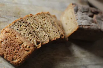Loaf of mixed grain bread with several slices in front of it.