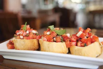Rectangular plate with three portions of tomato basil bruschetta.